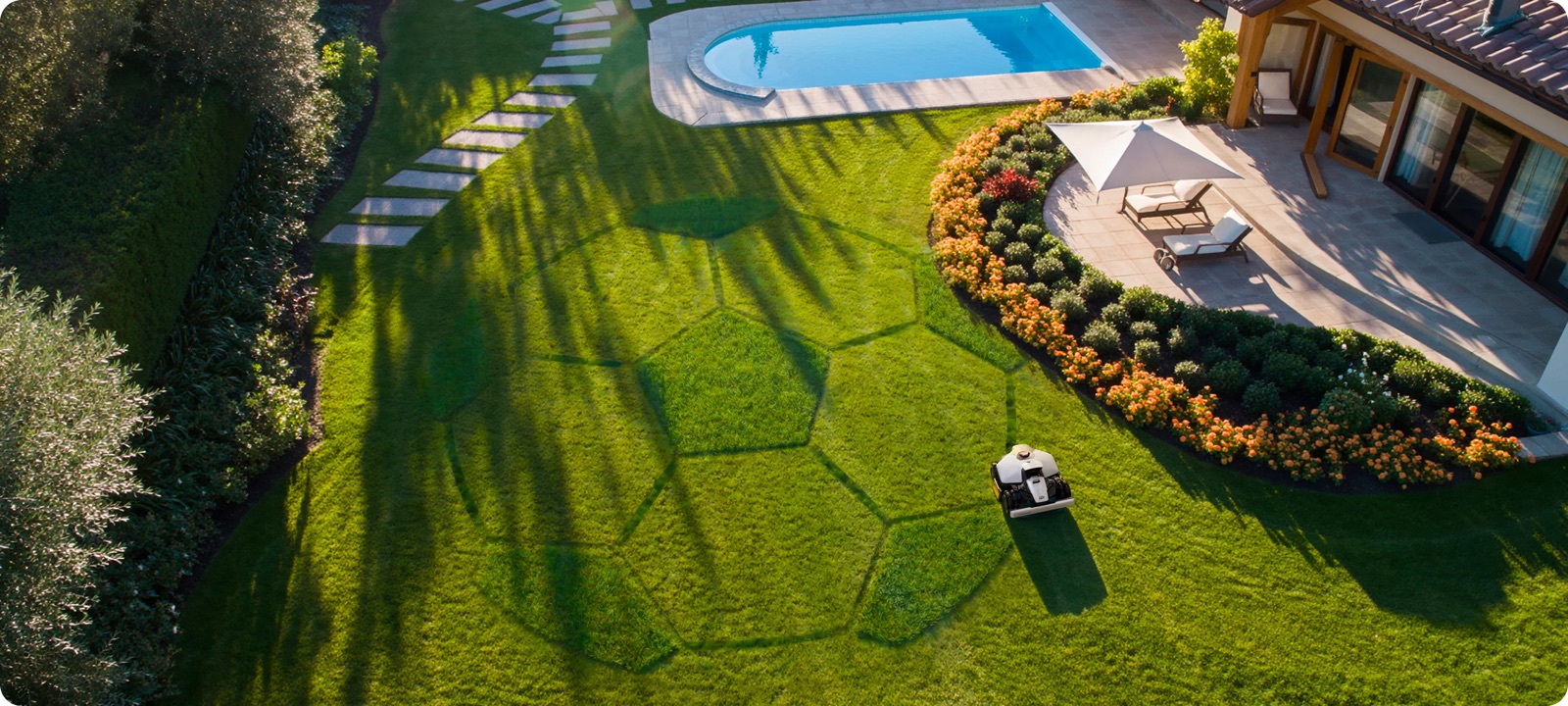 Mammotion LUBA robot mower cutting hexagonal patterns on a premium residential lawn with a swimming pool